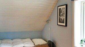 A small, single-bed room with a sloped ceiling, a bedside table, a framed picture on the wall, and a window with a view of greenery. - 5 Person Holiday Home in Lonashult (Lönashult)