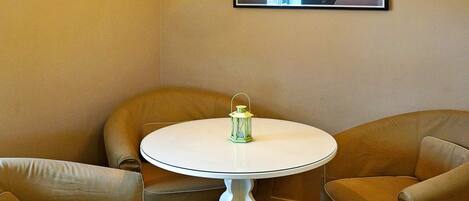 A room with a round table, two chairs, a hanging light fixture, and a framed picture on the wall.