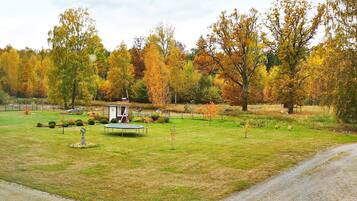 A rural landscape with a small gazebo, a dirt path, and autumn-colored trees.