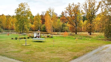 A park with a small gazebo, a circular trampoline, and a gravel path.