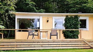 A wooden deck with a table and chairs, a small window, and a door leading to an interior space. - 2 Person Holiday Home in Tyringe-by Traum (Tyringe)