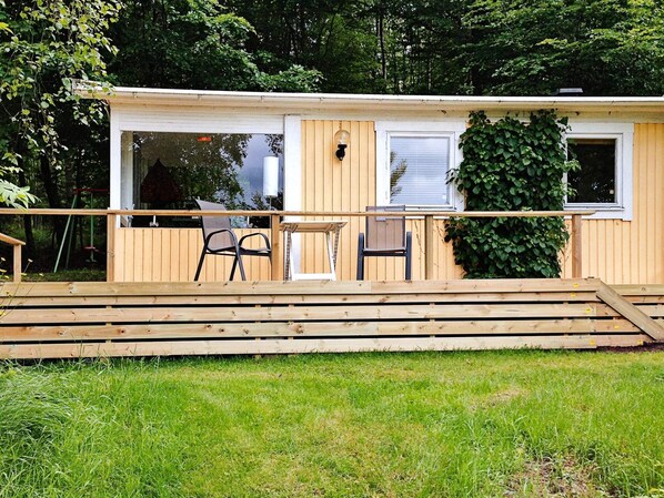 A wooden deck with a table and chairs, a small window, and a door leading to an interior space. - 2 Person Holiday Home in Tyringe (Tyringe)