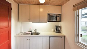 Kompakti keittiö, jossa on puukaapit, mikroaaltouuni, kahvinkeitin ja astianpesukone.