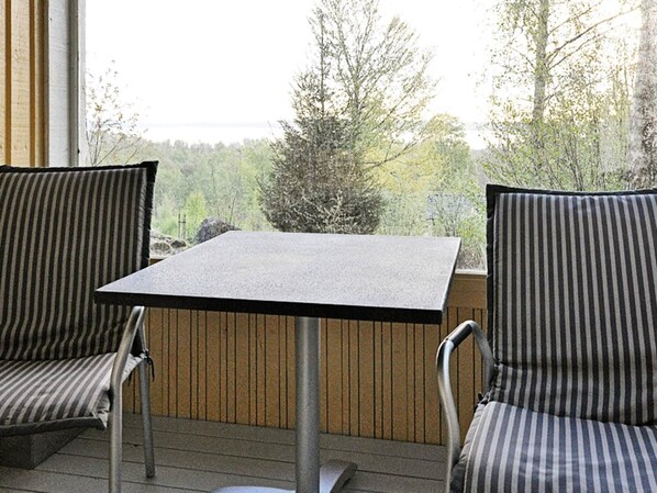 A balcony with two striped chairs and a square table, overlooking a forested area. - 2 Person Holiday Home in Tyringe (Tyringe)