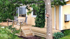 A wooden deck with a table and chairs, a birdhouse, and a small garden area. - 2 Person Holiday Home in Tyringe-by Traum (Tyringe)