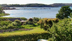A lakeside view with a dock extending into the water, surrounded by greenery and buildings. - 4 Person Holiday Home in Hamburgsund (Hamburgsund)