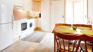 A compact kitchen with white cabinets, a washing machine, and a dining area with a table and chairs. - 4 Person Holiday Home in Hamburgsund (Hamburgsund)