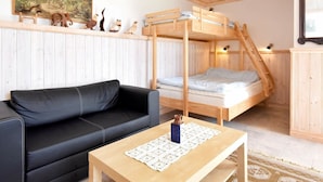 A cozy room with a bunk bed, a black leather sofa, a wooden table with a lace tablecloth, and a painting on the wall. - 4 Person Holiday Home in Hamburgsund (Hamburgsund)