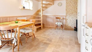 A dining area with a wooden table and chairs, a spiral staircase, and a tiled floor. - 4 Person Holiday Home in Hamburgsund (Hamburgsund)