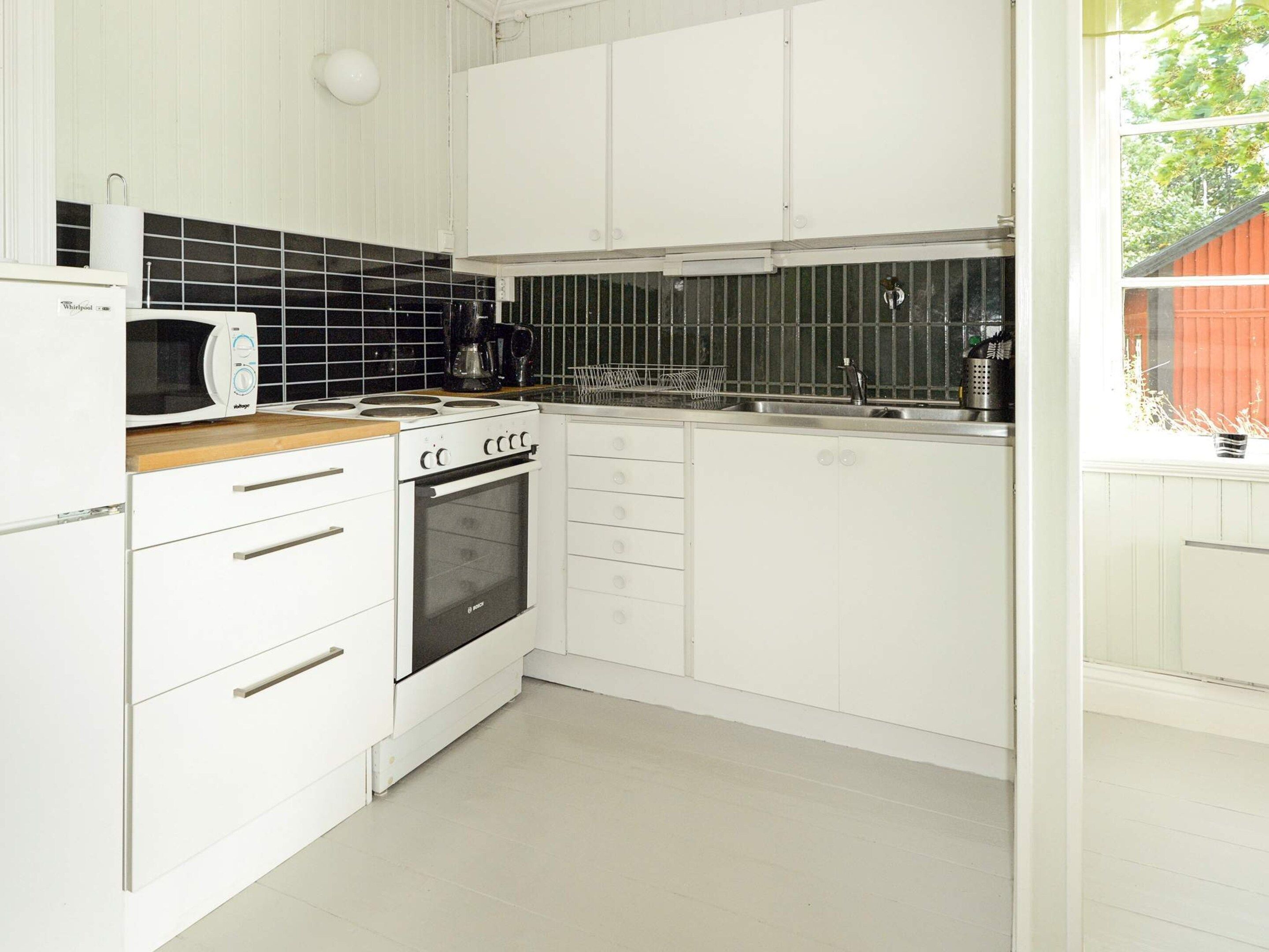 A kitchen with white cabinets, a microwave, an oven, and a coffee maker.