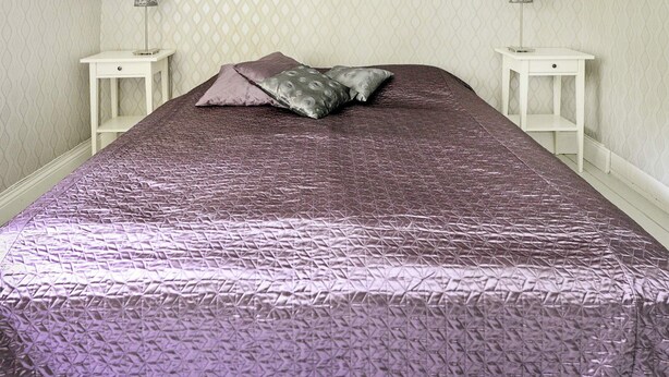 A bed with a textured purple bedspread, two bedside tables, and a patterned wall. - 5 Person Holiday Home in Mariefred (Mariefred)