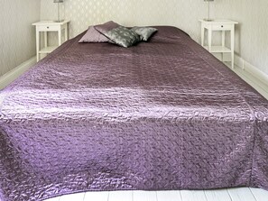 A bed with a textured purple bedspread, two bedside tables, and a patterned wall. - 5 Person Holiday Home in Mariefred (Mariefred)