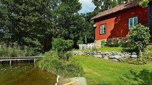 A lakeside property with a red house, a dock, and a small boat. - 5 Person Holiday Home in Mariefred (Mariefred)