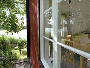 A room with a large window overlooking a garden and a body of water. - 5 Person Holiday Home in Mariefred (Mariefred)