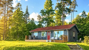 A cabin with a red roof, large windows, and a deck with outdoor seating. - Holiday Home in HÃ¥cksvik (Håcksvik)