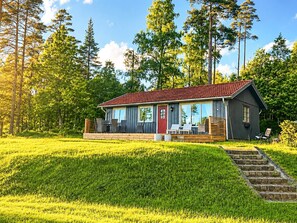 A cabin with a red roof, large windows, and a deck with outdoor seating. - Holiday Home in H Ã¥cksvik (Håcksvik)