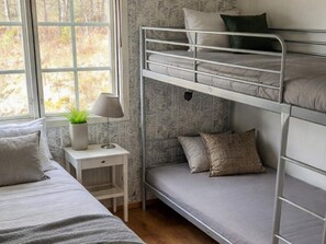 A bunk bed room with a window, a bedside table with a lamp, and a small plant. - Holiday Home in HÃ¥cksvik (Håcksvik)