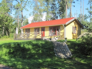 A yellow building with a red roof, a wooden fence, and a stone staircase leading to the entrance. - Holiday Home in HÃ¥cksvik (Håcksvik)