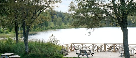 Zona de picnic junto al lago con bancos y mesas.