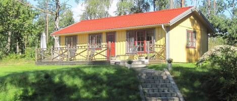 A yellow building with a red roof, wooden fence, and a stone staircase leading to the entrance.
