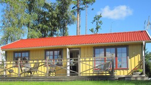 A yellow building with a red roof, a wooden fence, and a grassy foreground. - Holiday Home in HÃ¥cksvik (Håcksvik)