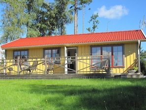 A yellow building with a red roof, a wooden fence, and a grassy foreground. - Holiday Home in HÃ¥cksvik (Håcksvik)