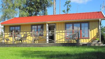 A yellow building with a red roof, a wooden fence, and a grassy area in front.