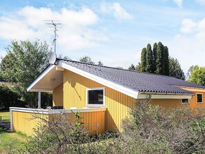 A single-story wooden house with a sloped roof, a satellite dish, and a small attached garage. - 4 Star Holiday Home in Stege (Stege)