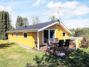 A yellow cabin with a patio, a barbecue grill, and a satellite dish. - 4 Star Holiday Home in Stege (Stege)