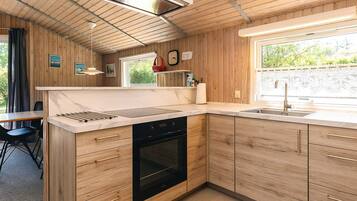 Una cocina moderna con muebles de madera, horno integrado y ventana que proporciona luz natural.