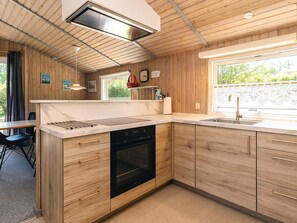 Een moderne keuken met houten kastjes, een ingebouwde oven en een raam dat voor natuurlijk licht zorgt.