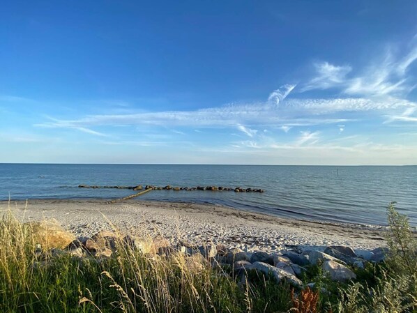 A beach with a rocky shoreline, calm water, and a clear sky.