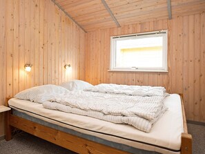 A wooden-paneled room with a bed, two wall-mounted lights, and a window. - 4 Star Holiday Home in Stege (Stege)