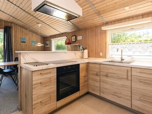 A modern kitchen with wooden cabinetry, a built-in oven, and a large window providing natural light. - 4 Star Holiday Home in Stege (Stege)