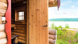 A wooden cabin with a door open, revealing a window and a view of a lake. - Holiday Home in SÃ¤len (Lima)
