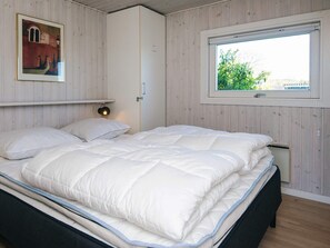 A bedroom with a bed, a window, a door, and a wall-mounted lamp. - 4 Star Holiday Home in Sjolund (Sjølund)