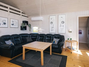 A modern living room with a sectional sofa, a wooden coffee table, and artwork on the walls. - 4 Star Holiday Home in Sjolund (Sjølund)