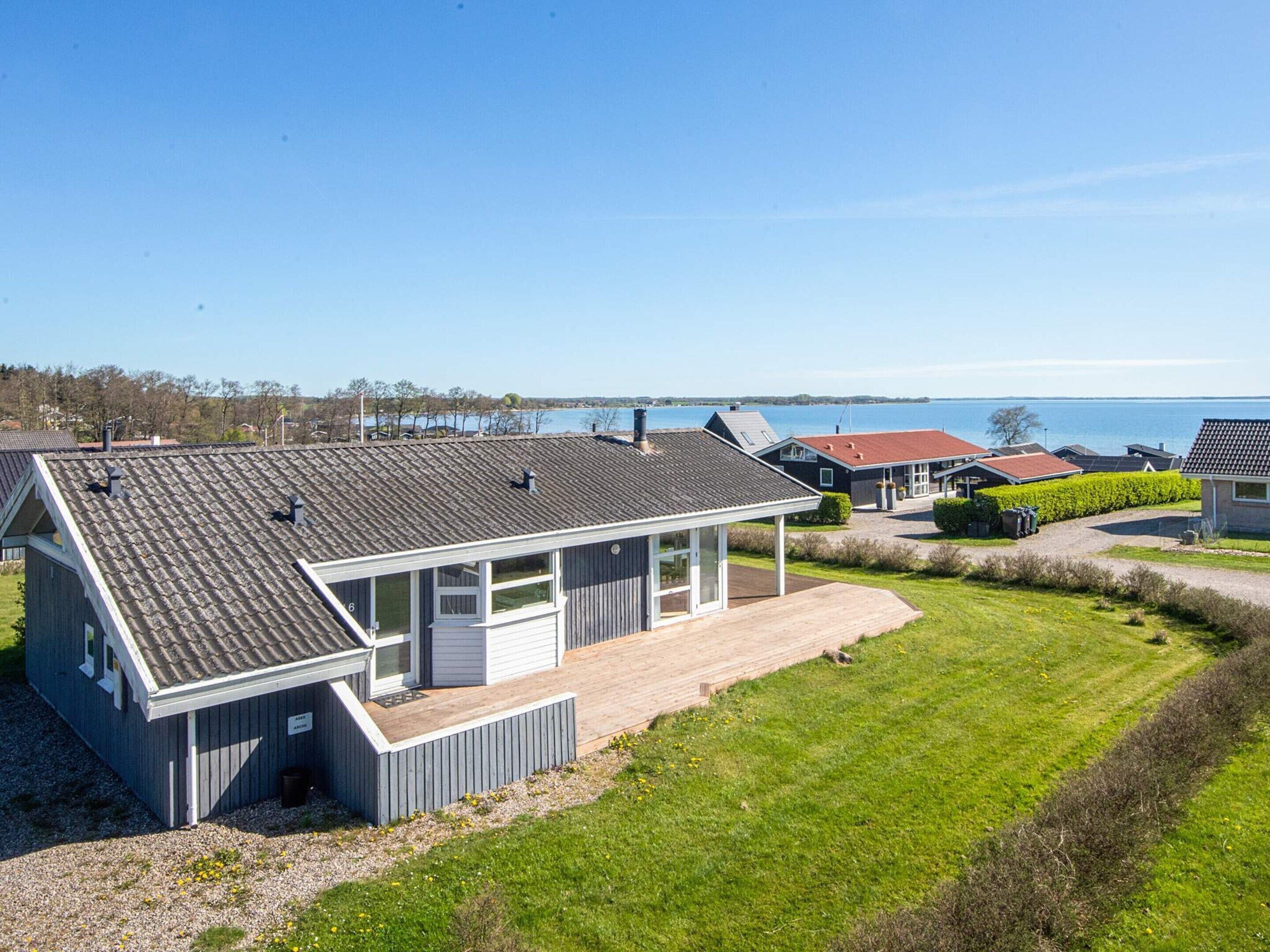 A modern house with a sloped roof, a covered porch, and a view of the sea.