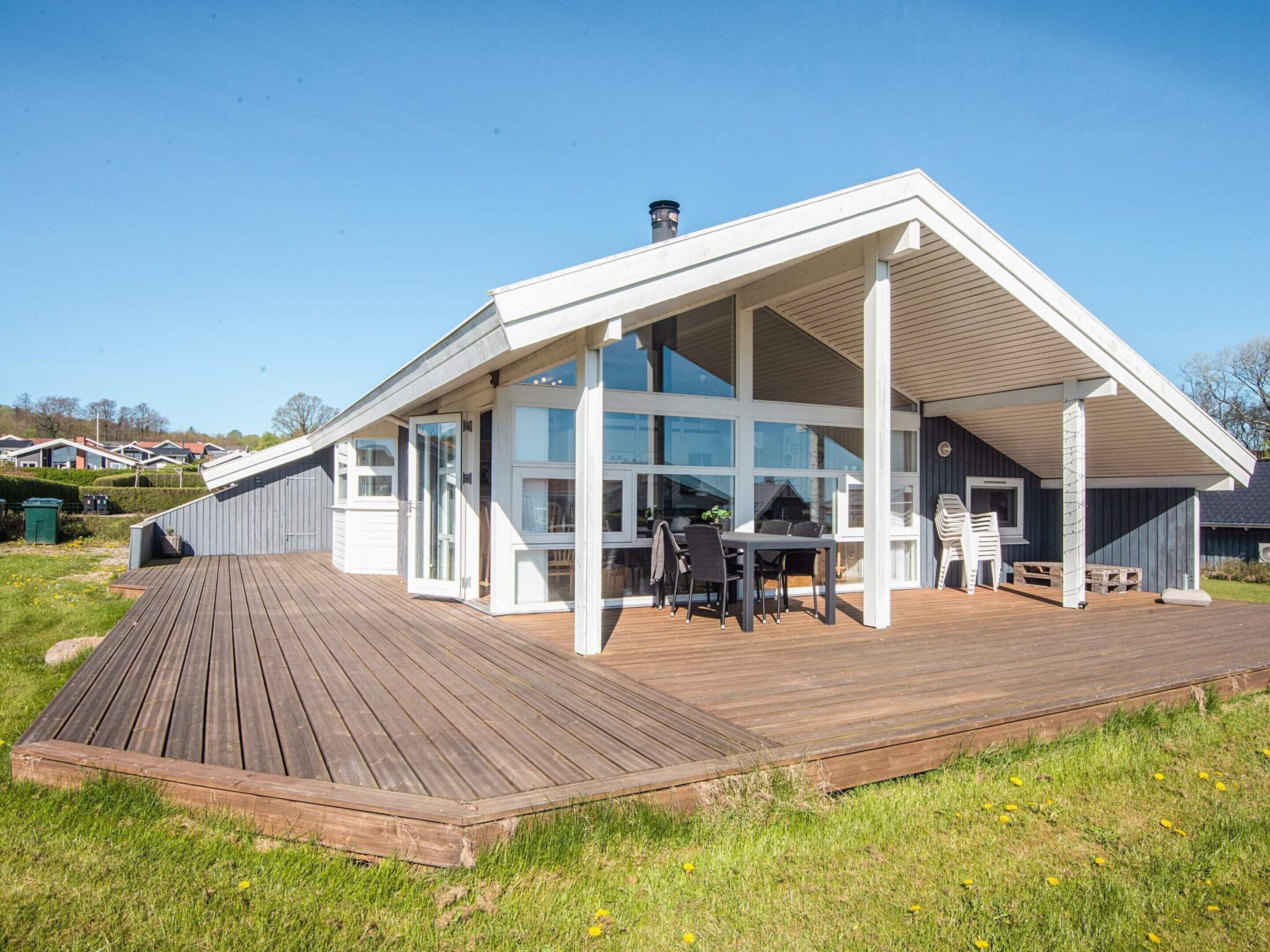 A modern house with a large deck, a covered outdoor seating area, and a chimney.