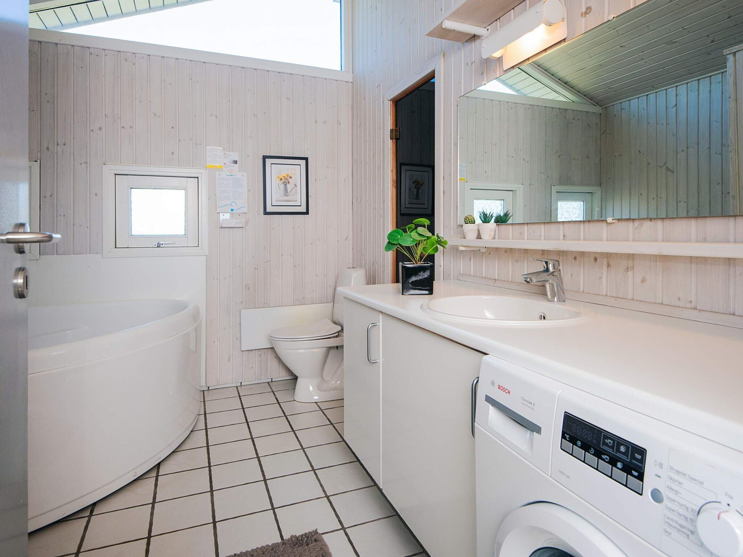 A modern bathroom with a bathtub, toilet, sink, and washing machine.