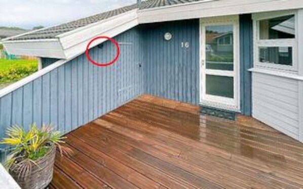 A residential property with a wooden deck, a blue exterior wall, and a white door.