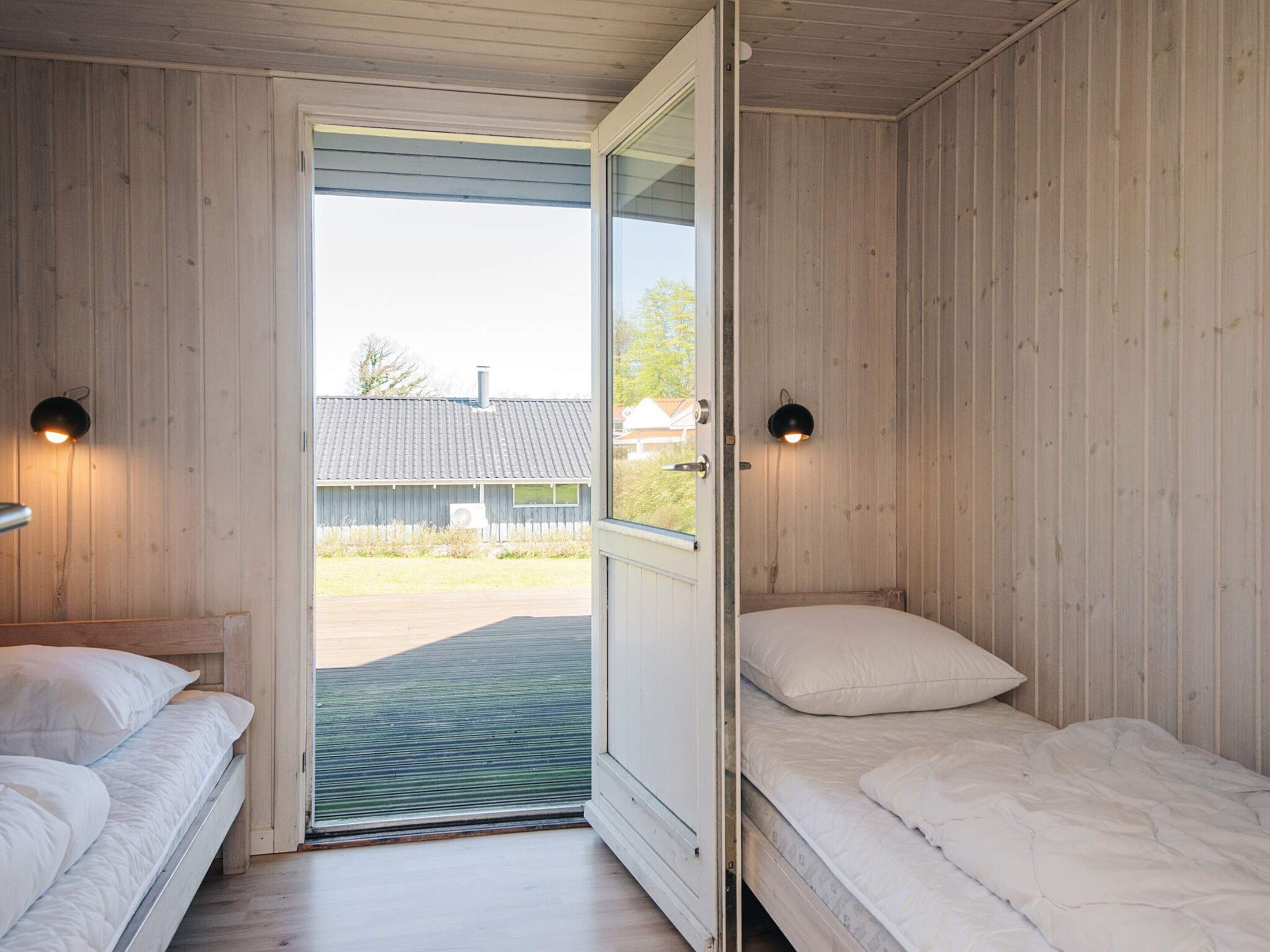 A room with two beds, a door leading outside, and two wall-mounted lights.