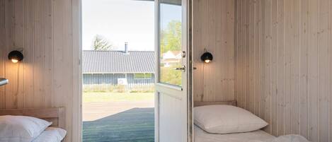 A room with two beds, a door leading outside, and two wall-mounted lights.