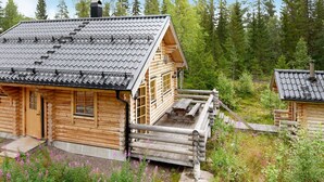 A log cabin with a sloped roof, a wooden deck, and a surrounding natural landscape. - Holiday Home in SÃ¤len (Lima)