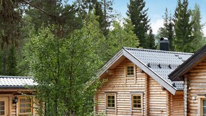 Une cabane en rondins avec un toit en pente, de nombreuses fenêtres et une cheminée.