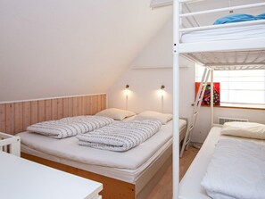 A dorm-style room with bunk beds, a wooden headboard, two wall-mounted lights, and a window with a colorful painting. - 4 Star Holiday Home in Allingabro (Allingåbro)