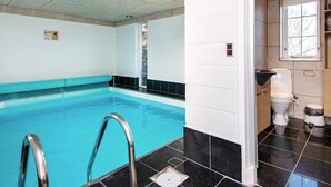 A swimming pool with a metal ladder, a white wall with a window, and a toilet area with a sink. - 4 Star Holiday Home in Allingabro (Allingåbro)