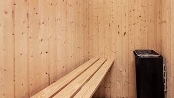 Una sauna con pareti in legno, una panca e una stufa sauna nera.