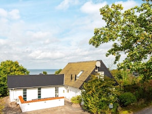 A two-story house with a sloped roof, a satellite dish, and a view of the sea. - 4 Star Holiday Home in Allingabro (Allingåbro)
