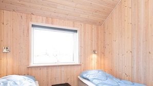 Ein Zimmer mit zwei Betten, einem Fenster und einem kleinen, schwarzen Hocker.
